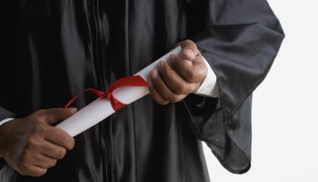 Mid section of man in graduation gown holding diploma