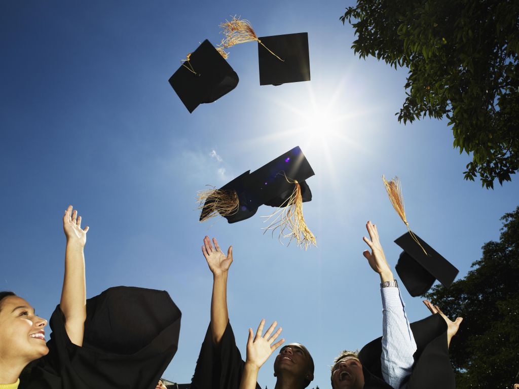 Group of graduates throwing mortar boards in air