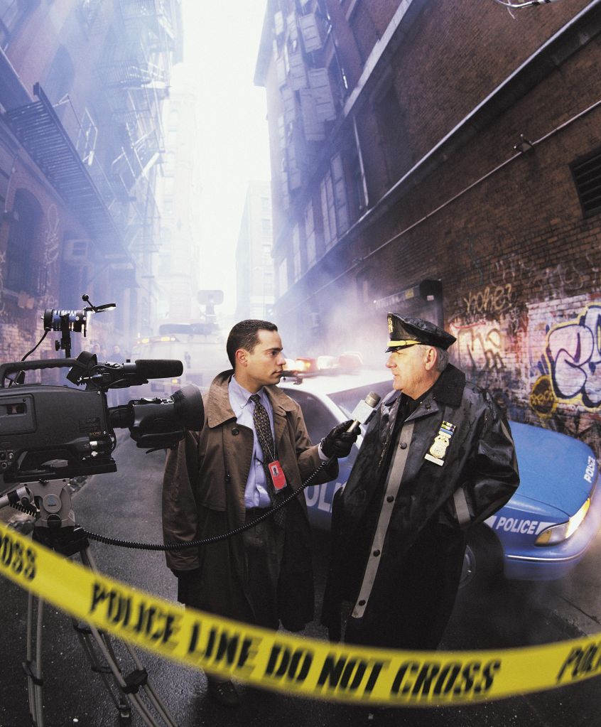News reporter with police officer at crime scene, New York, USA