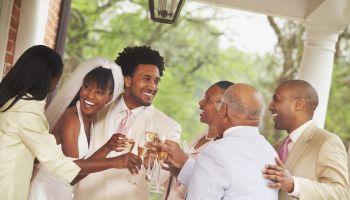 African American newlyweds toasting with family