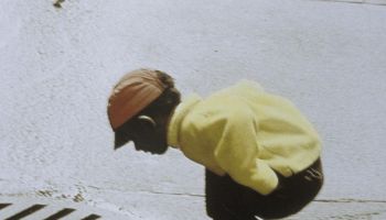 Boy bending over sewage drain, Salem, Massachusetts