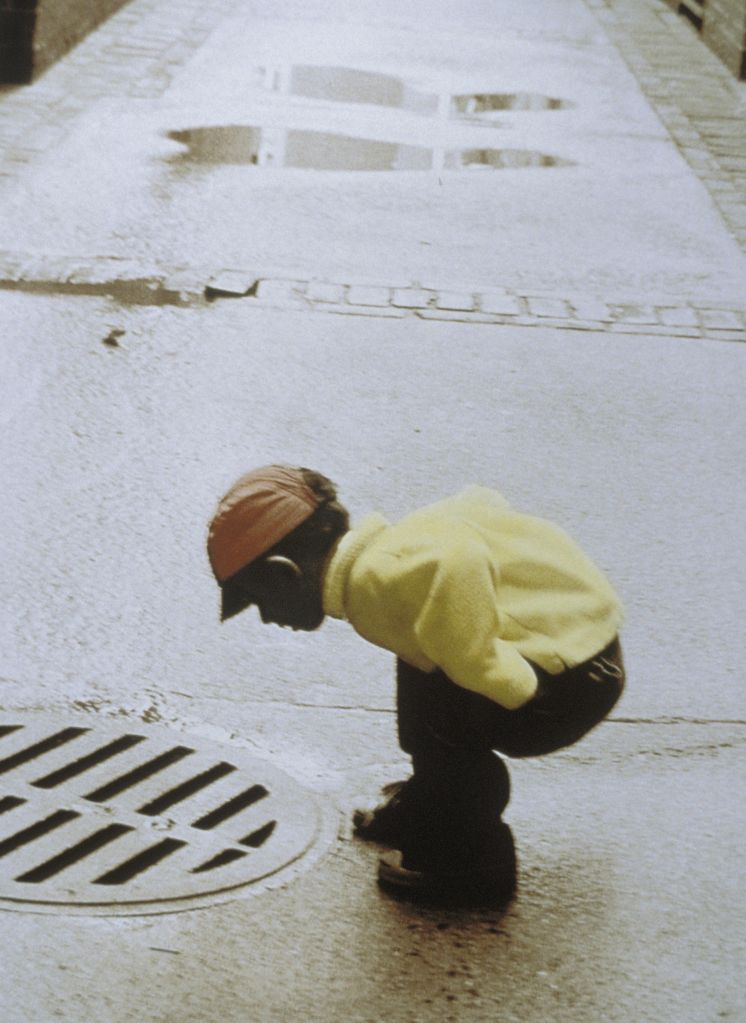 Boy bending over sewage drain, Salem, Massachusetts