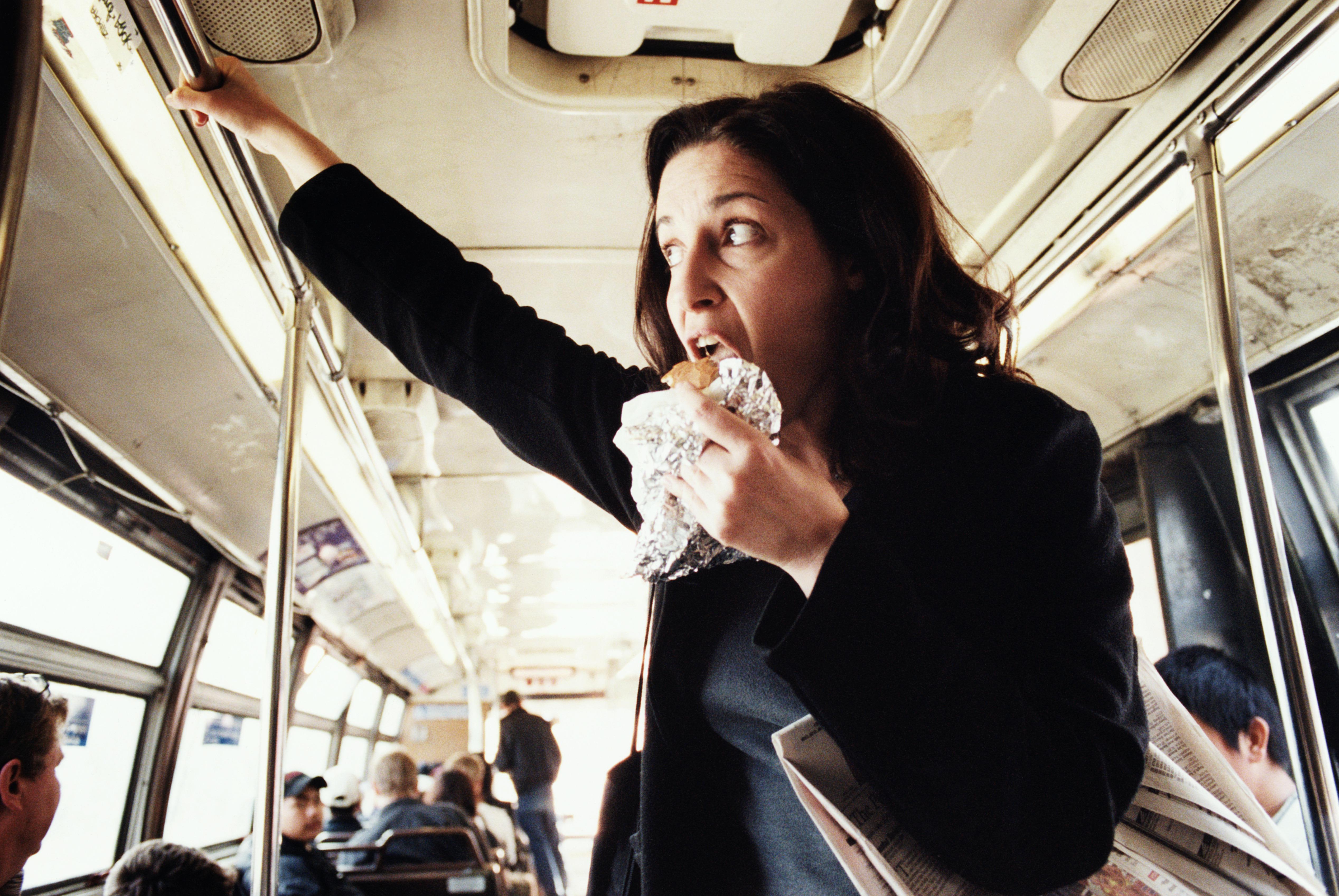 Woman eating hamburger on bus