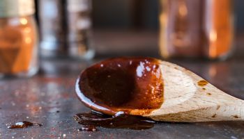 Close-Up Of Barbecue Sauce On Wooden Spoon At Table