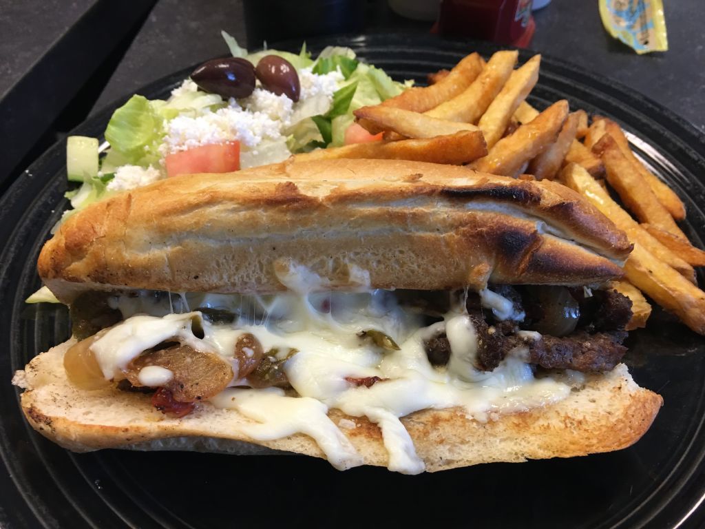 Close-Up Of Philadelphia Cheese Steak With Greek Salad In Plate