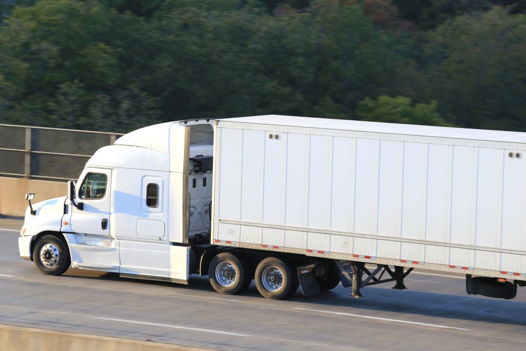 Side view of a moving semi truck on a highway bridge