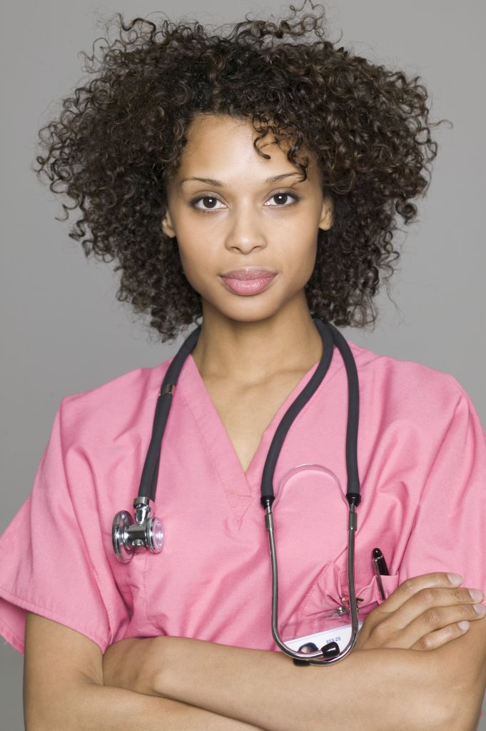 portrait of a young adult female nurse in pink scrubs as she folds her arms