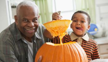 Grandfather and grandson carving a pumpkin