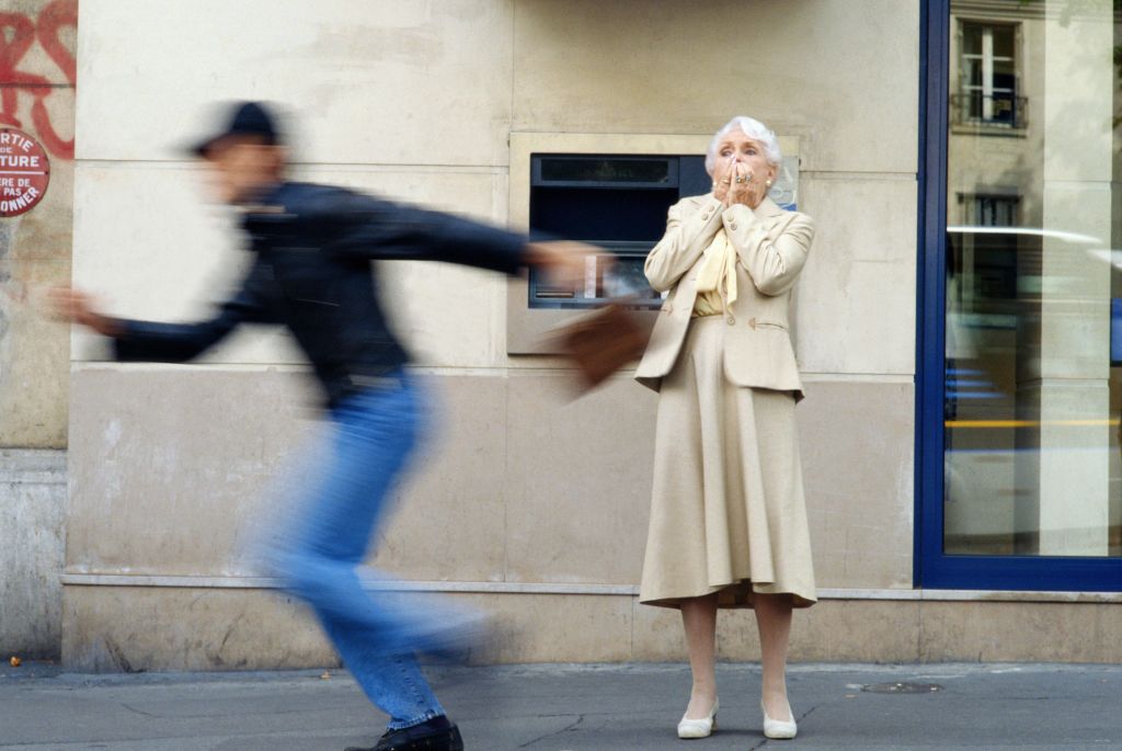 Thief stealing elderly woman's handbag