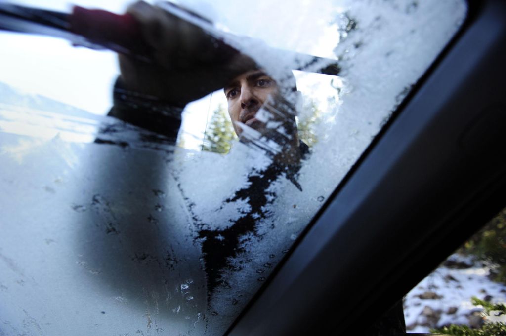 Neel Kashkari scraping frost from the windshield of his SUV