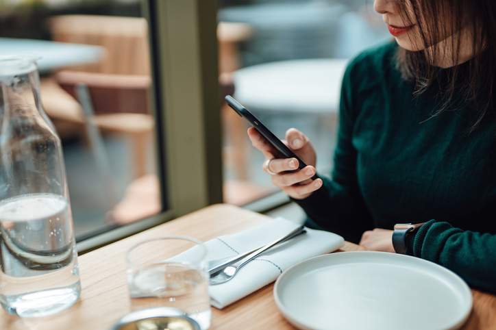 Young Woman Using Smart Phone While Relaxing At A Restaurant
