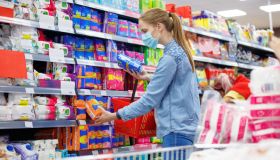 Woman choosing between two brands of sanitary napkins or tampons during coronavirus outbreak