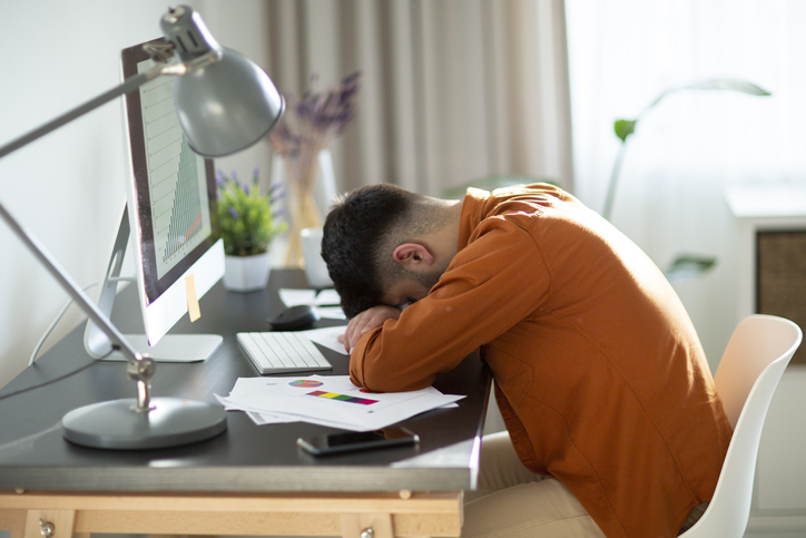 I need a vacation! Close up top view portrait of tired sick young brunet guy. He is wearing the formalwear, resting at the workplace