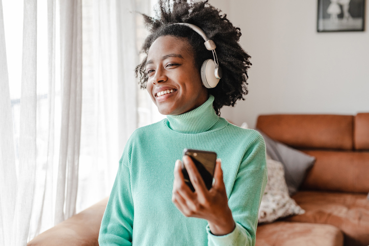 African-American woman is listening to music at home and holding mobile phone