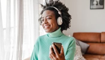 African-American woman is listening to music at home and holding mobile phone