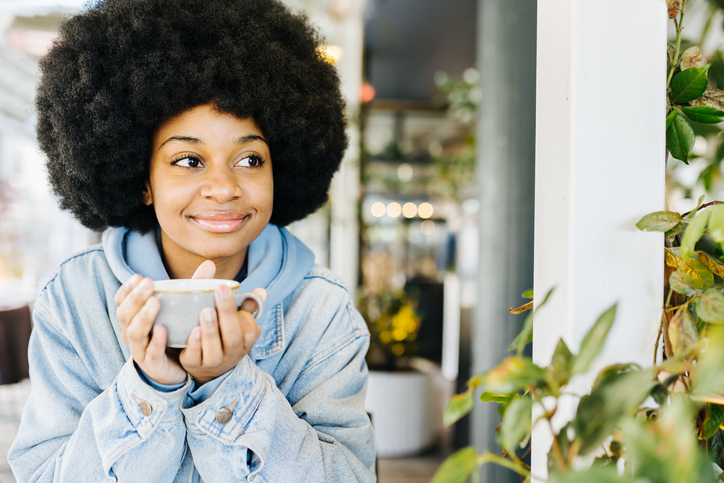 Thoughtful afro woman relaxing while drinking a cup of coffee
