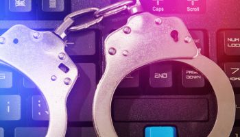 Metal handcuffs on computer keyboard, internet cybercrime