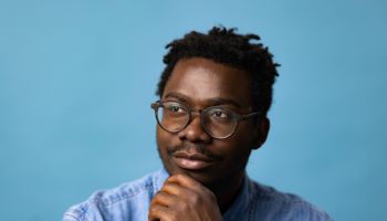 Young black man day dreaming against blue background.