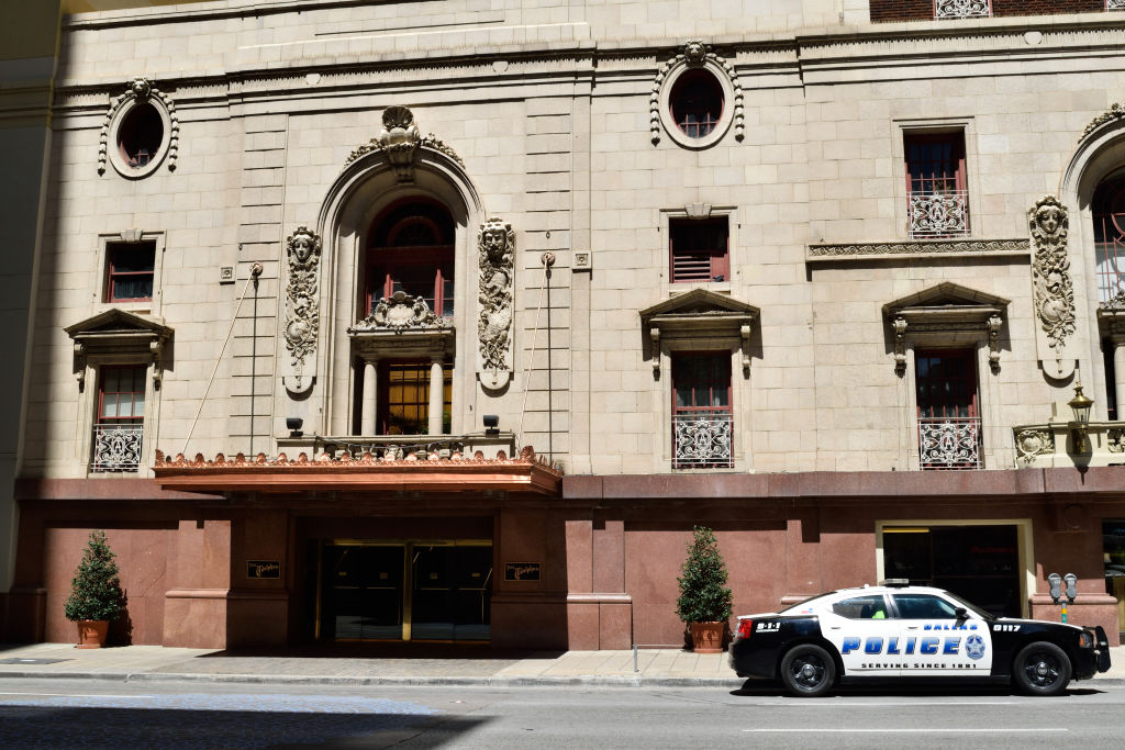 A police car parked in front of the Adolphus Hotel building in downtown Dallas, TX