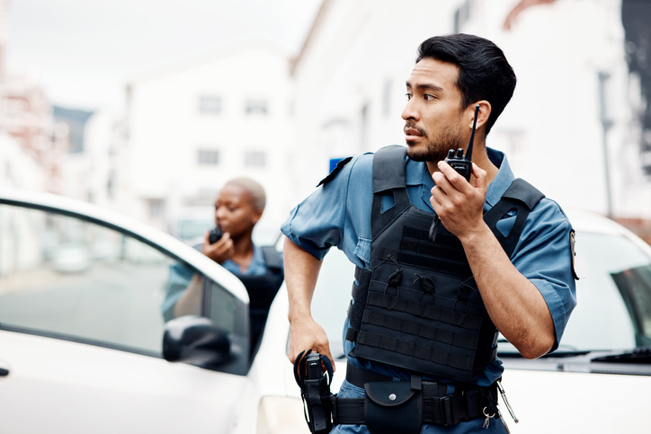 Police, emergency and officer with gun calling backup for an investigation or law protection in city or urban town. Criminal, radio and legal service team or security on duty for justice enforcement