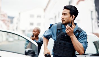 Police, emergency and officer with gun calling backup for an investigation or law protection in city or urban town. Criminal, radio and legal service team or security on duty for justice enforcement