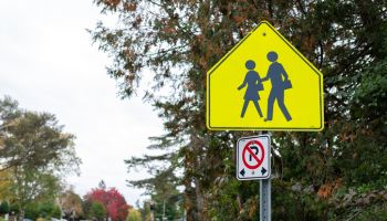 Yellow school crossing ahead sign on the road near school zone