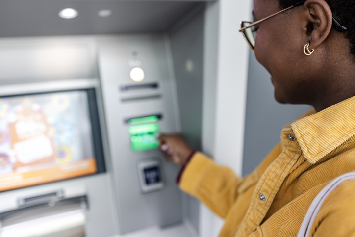 A woman inserting a debit card into an ATM