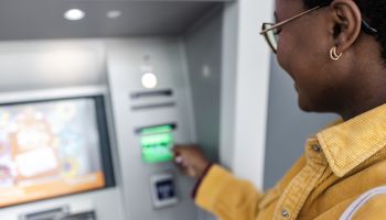 A woman inserting a debit card into an ATM