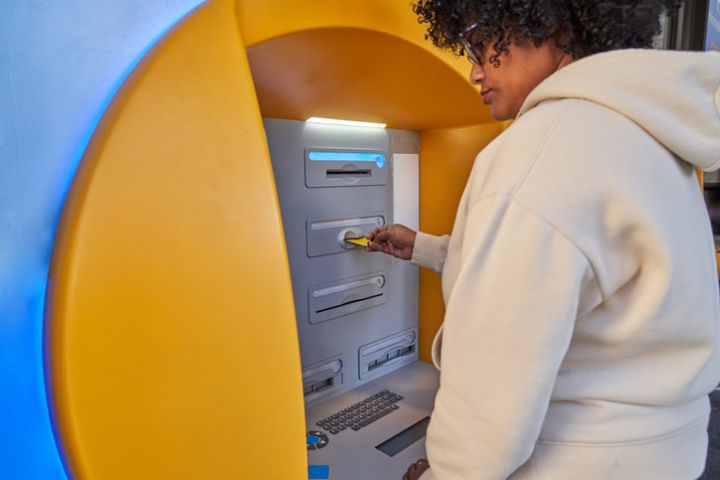 Young Black Woman Using ATM Automated Teller Machine to withdraw money