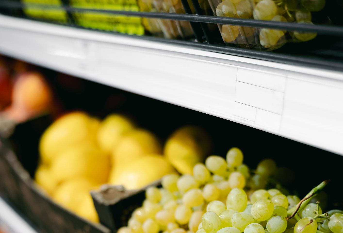 Close-up of supermarket grapes in trays on shelves, copy space.