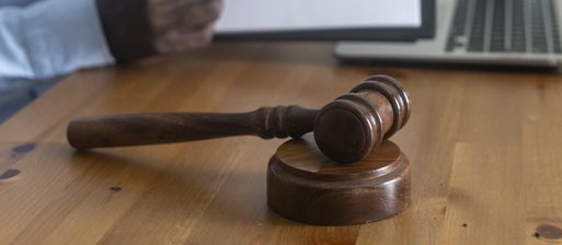 Person pointing at legal document with gavel and laptop on table