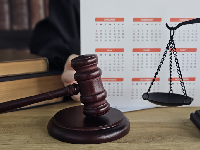 Gavel and balance scale on a desk with a calendar in a courtroom setting during a legal consultation concept