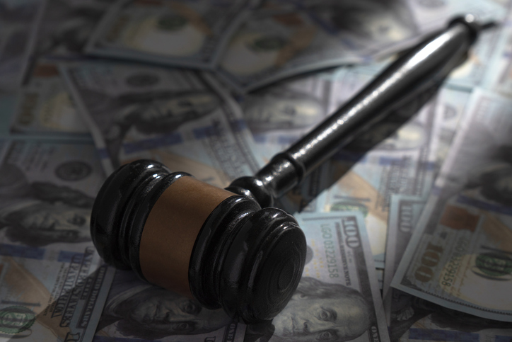 Black gavel on a pile of one hundred US dollar bills.