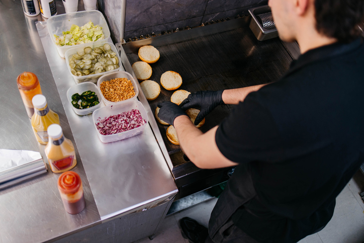 Chefs making hamburgers in restaurant kitchen