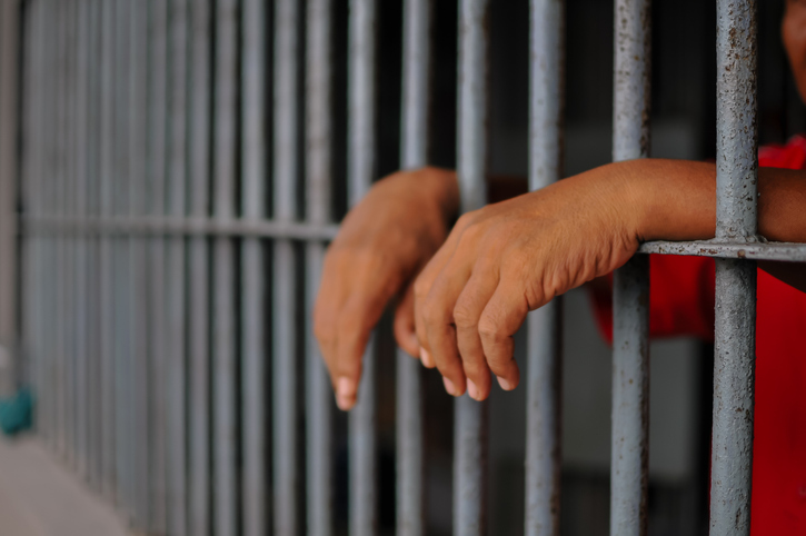 prisoner's hands behind bars