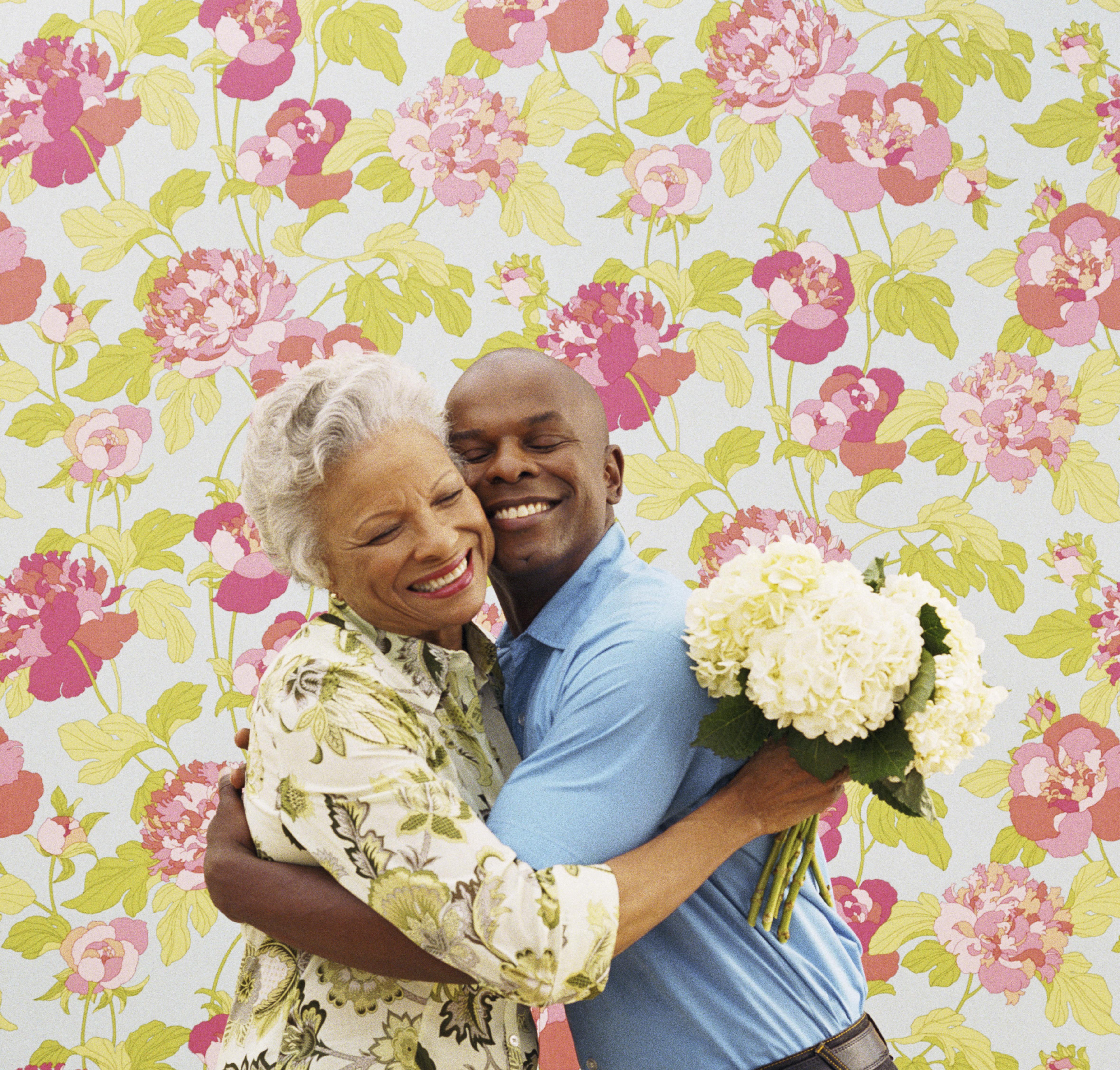 Woman and man embracing with bouquet of flowers