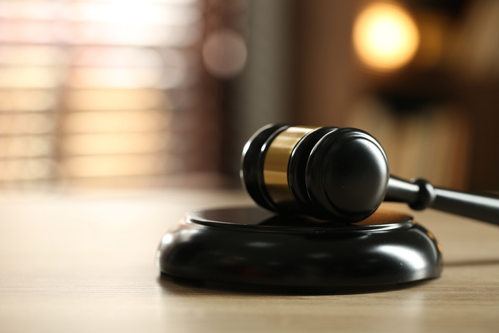 Judge's gavel on wooden table against blurred background, closeup