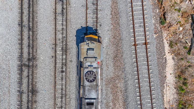 train transporting cargo along a railway line in a scenic landscape during daylight
