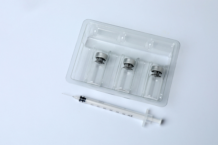 Syringe and bottles with coronavirus medicine. Colored bottles with medicine on a white background.