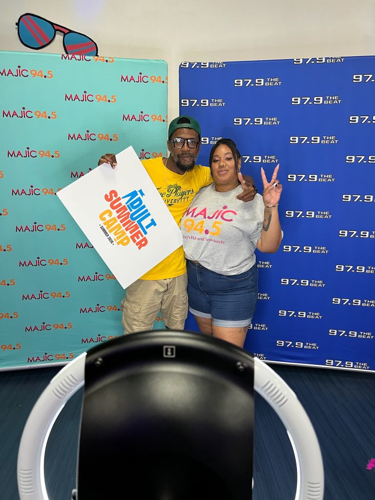 Two people posing in front of Majic 94.5 radio station branding, holding a "Soul Summer Jam" sign and making peace signs.