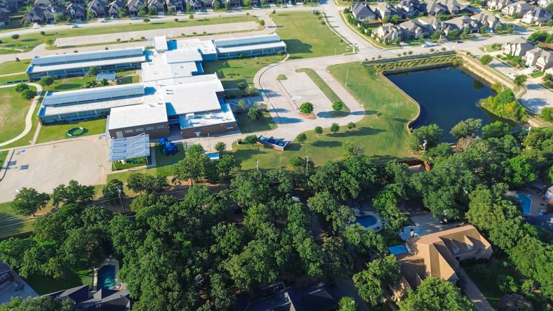 School-centered planning with Elementary School surrounding suburban homes, adjacent pond in Lantana, Texas, track and field, mansion houses. Highlight environmental integration in suburb Dallas
