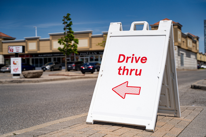 Close up of drive thru direction sign near commercial plaza