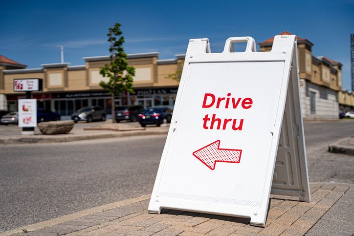 Close up of drive thru direction sign near commercial plaza